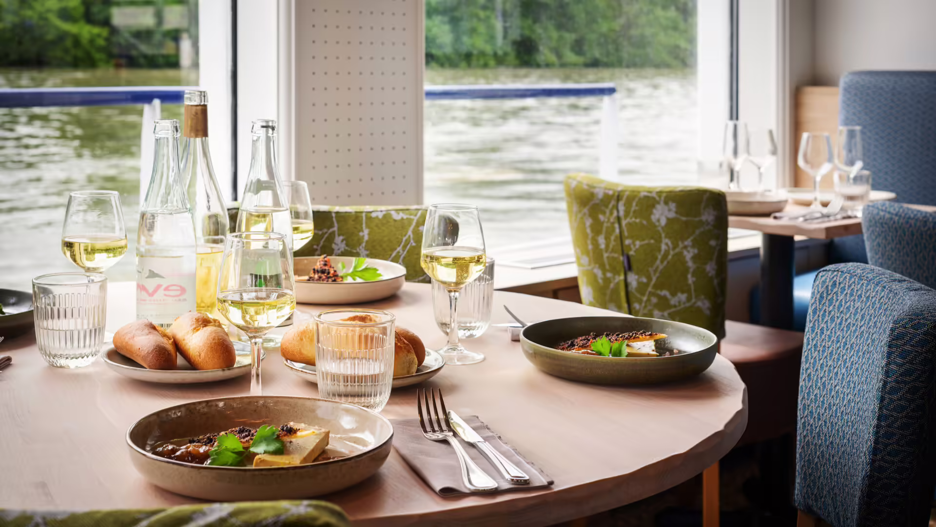 Table élégante dressée pour un dîner croisière sur la Seine à Paris, avec vue sur l'eau et mets raffinés | Le Capitaine Fracasse