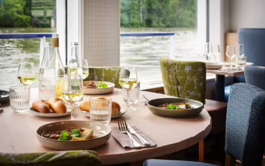 Table élégante dressée pour un dîner croisière sur la Seine à Paris, avec vue sur l'eau et mets raffinés | Le Capitaine Fracasse