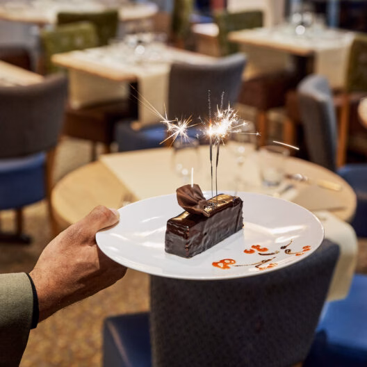 Dessert gourmand avec cierges magiques servi lors d'un dîner croisière sur la Seine à Paris, créant une ambiance festive et élégante | Le Capitaine Fracasse