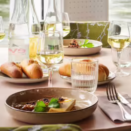 Table élégante dressée pour un dîner croisière sur la Seine à Paris, avec vue sur l'eau et mets raffinés | Le Capitaine Fracasse