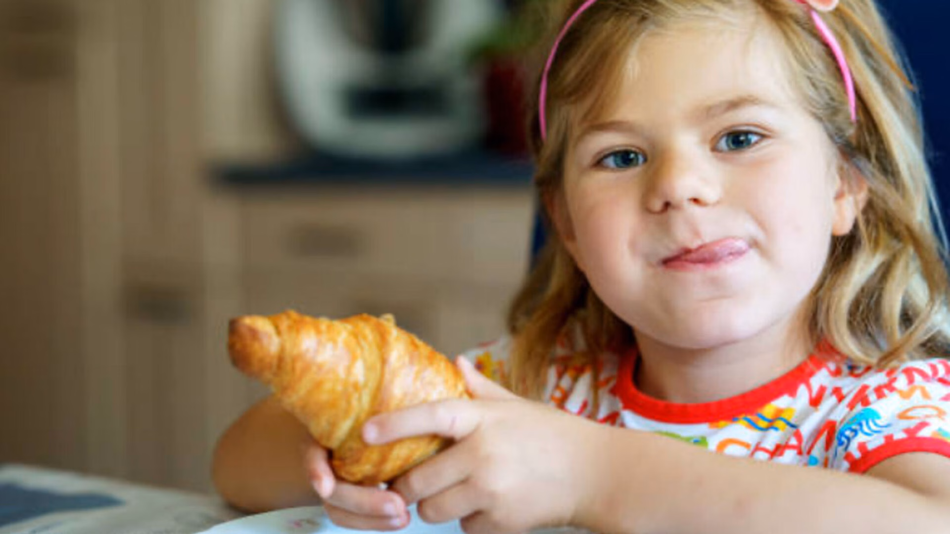 Jeune fille dégustant un croissant, symbole de la tradition culinaire française et du petit-déjeuner parisien | Moment gourmand et authentique