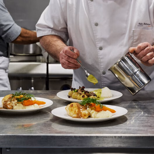 Chef préparant des plats gastronomiques pour un dîner croisière sur la Seine à Paris, mettant en valeur la cuisine française | Le Capitaine Fracasse