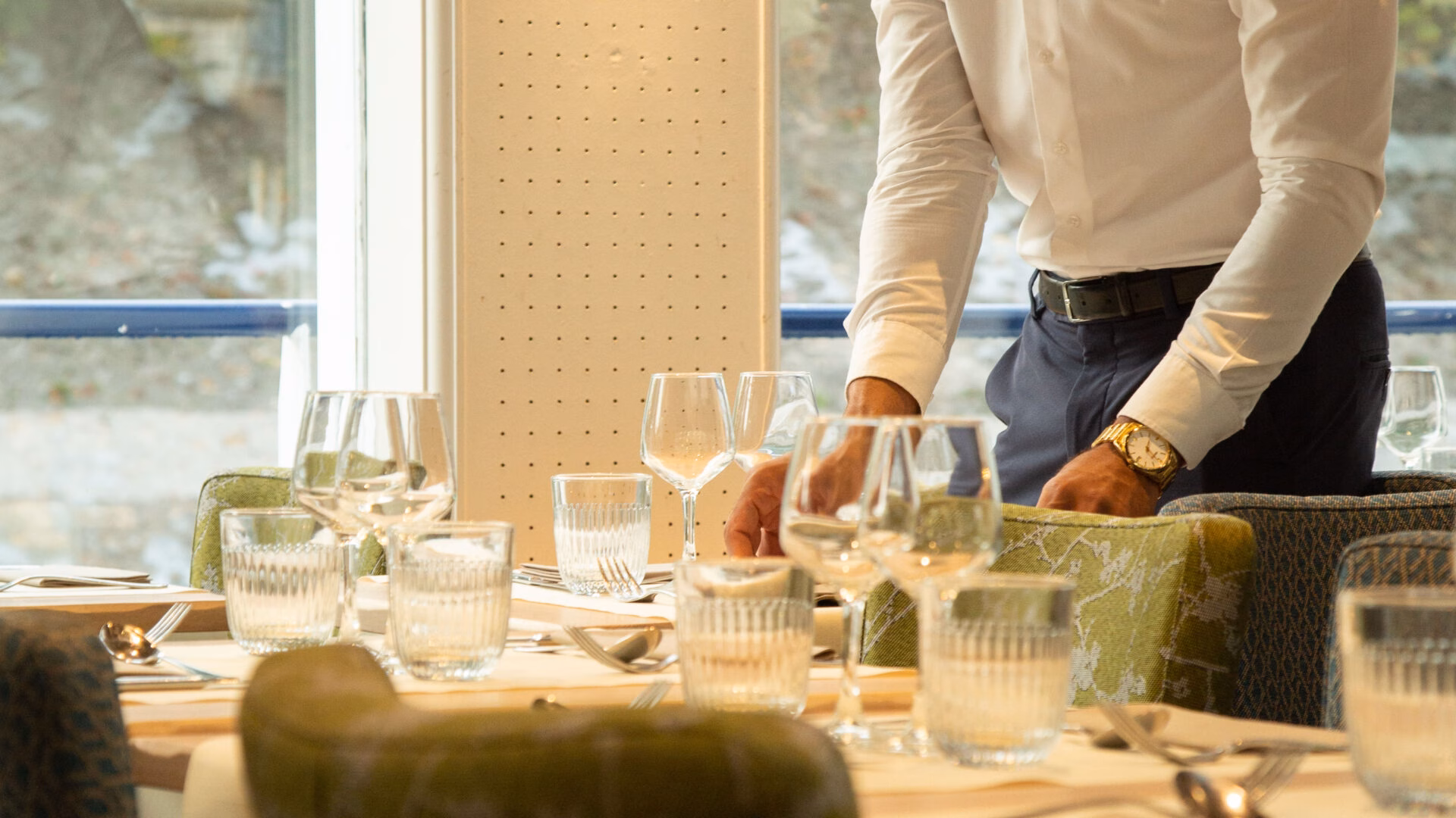 Serveur dressant une table élégante pour un dîner croisière sur la Seine à Paris, créant une atmosphère accueillante et raffinée | Le Capitaine Fracasse